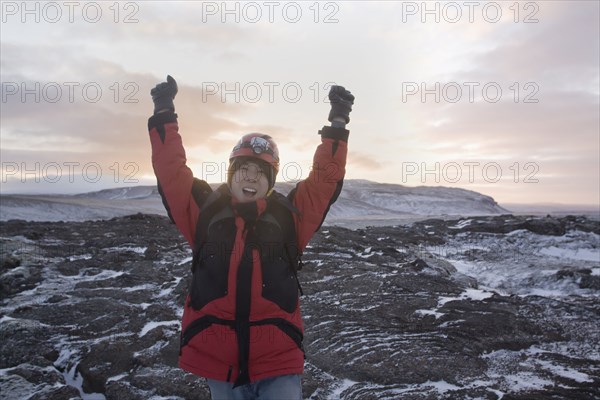 Chinese man standing with arms raised in remote ice field