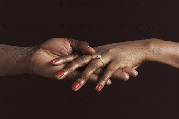 African woman with engagement ring holding fiancee's hand