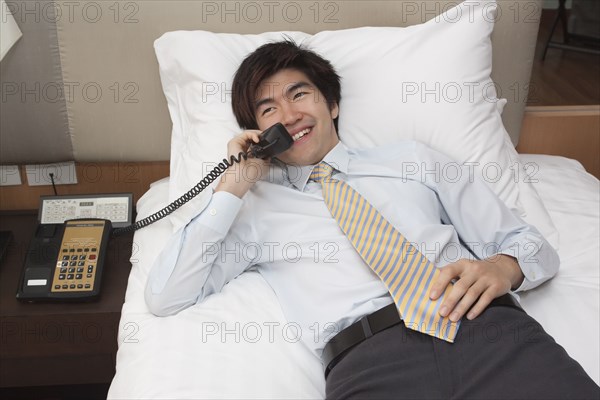 Chinese businessman on telephone in hotel room