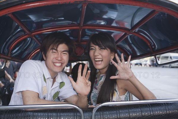 Asian couple in taxi waving