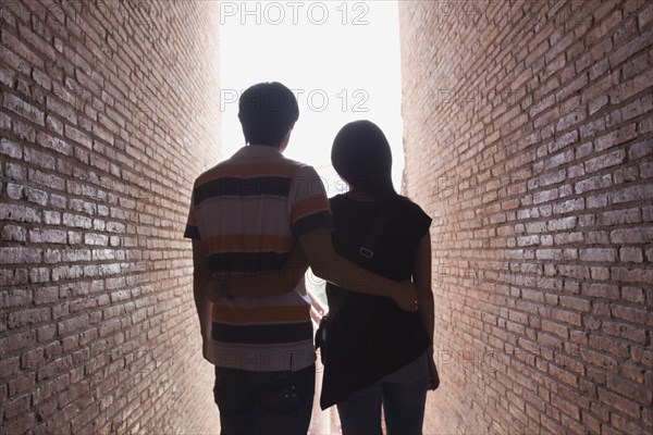 Asian couple walking between brick walls