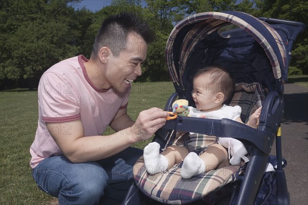 Chinese father and baby in stroller at park