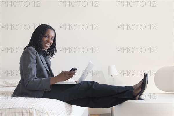 Mixed race businesswoman text messaging on cell phone