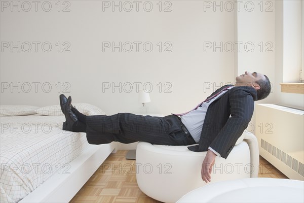Hispanic businessman napping in chair