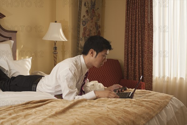 Chinese businessman using laptop in hotel room