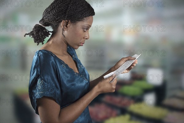 Black woman looking at grocery shopping list