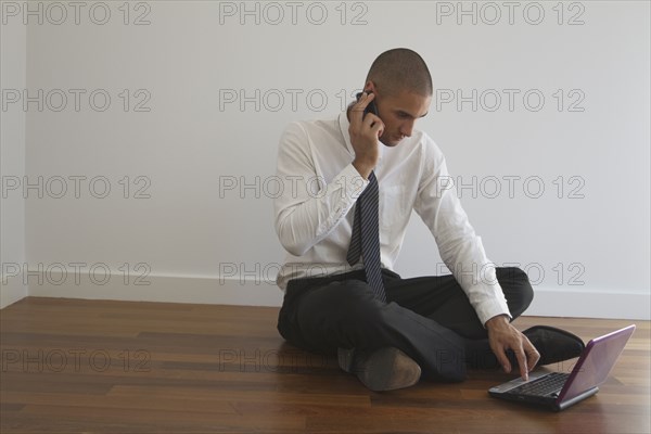 Mixed race businessman using laptop on floor