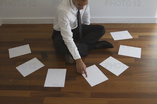 Mixed race businessman choosing paper on floor