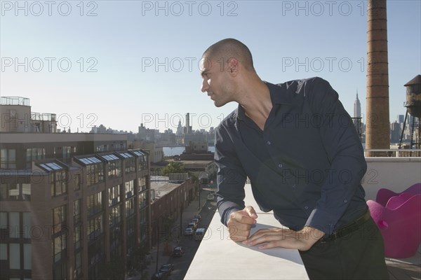 Mixed race man standing on urban balcony