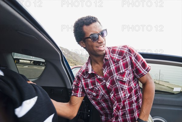 Mixed race man removing blanket from back of car