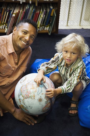 Father and son with globe in library