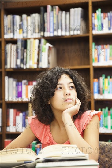 Mixed race girl doing homework in library