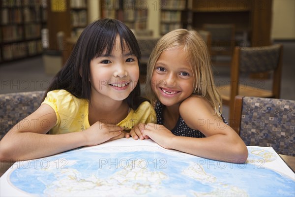 Girls looking at atlas in library