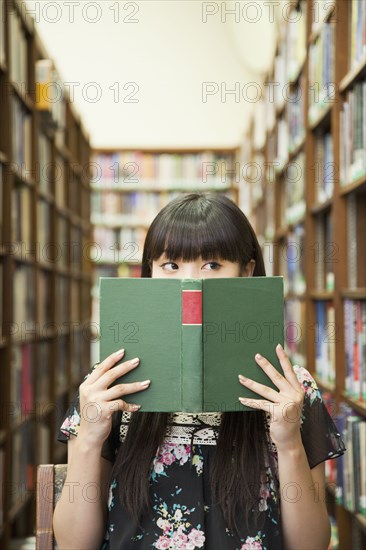 Asian woman reading book in library