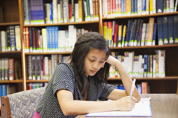 Asian girl doing homework in library