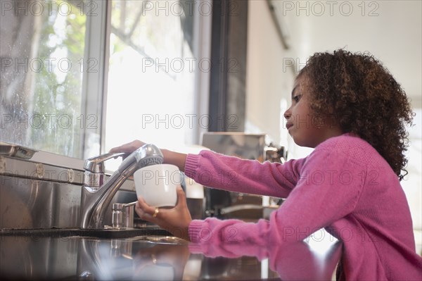 Mixed race girl washing dishes