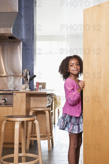 Mixed race girl opening kitchen cupboard