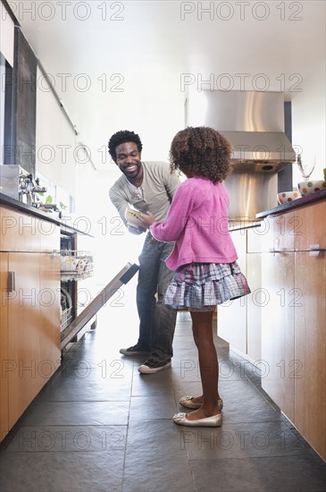 Father and daughter loading dishwasher