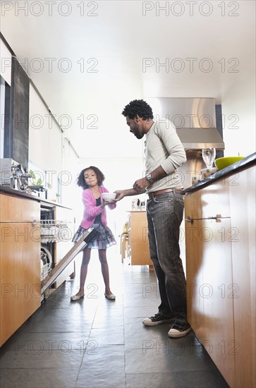 Father and daughter loading dishwasher
