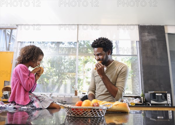 Father and daughter eating in kitchen