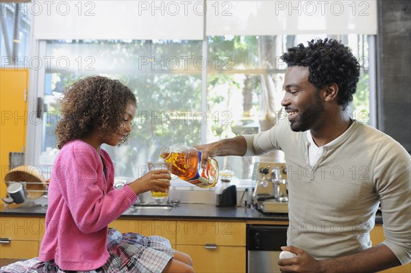 Father pouring juice for daughter