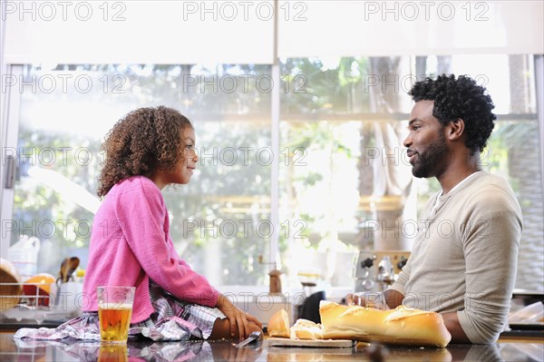 Father and daughter eating in kitchen