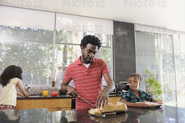 Father and daughters preparing food in kitchen