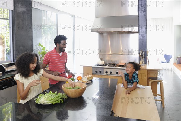 Father and daughters preparing food in kitchen