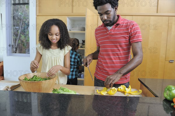 Father and daughters preparing food in kitchen