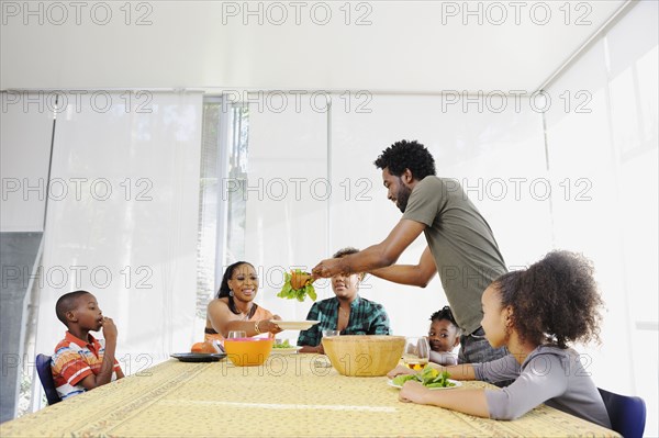 Black family eating salad at dining room table