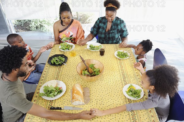 Black family saying grace at dining room table