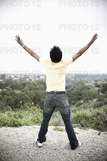 African American man with arms outstretched in remote area