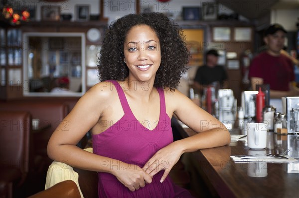 Smiling African American woman sitting at diner counter