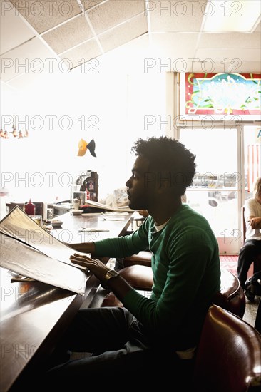 African American man reading menu at diner counter