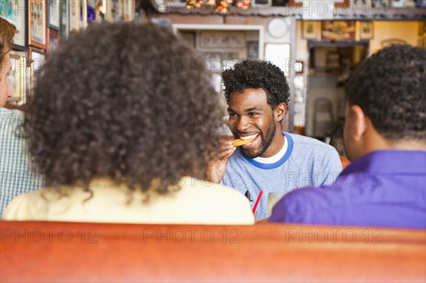 Smiling friends eating in diner booth