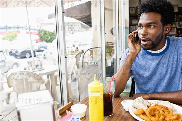 African American man talking on cell phone in diner