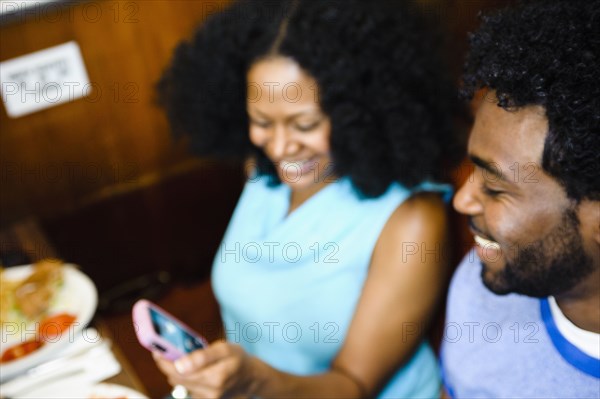 Smiling couple looking at cell phone in diner