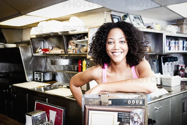 Smiling African American woman leaning on cash register in diner