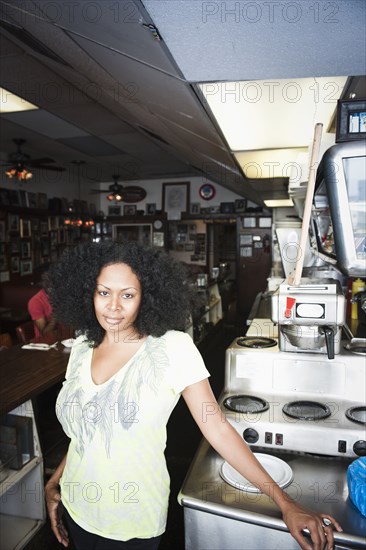 Smiling mixed race woman standing behind counter in diner