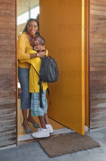 Black mother greeting son at front door