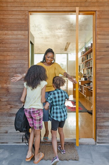 Black mother greeting daughters at front door