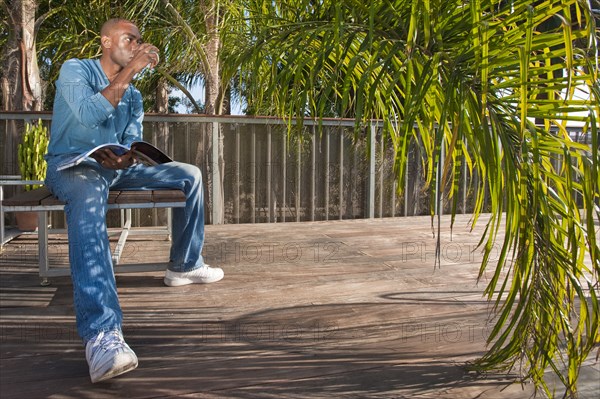 Black man reading book on patio