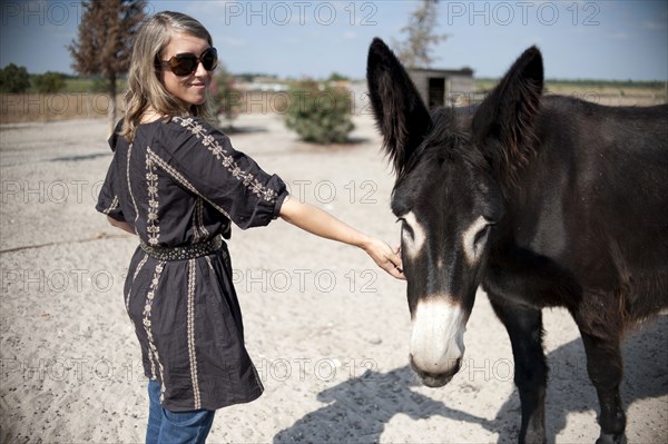 Caucasian woman petting donkey