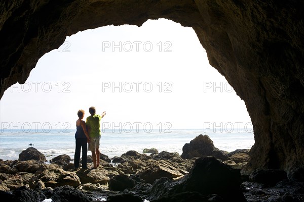 Couple standing in rocky beach cave