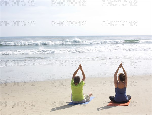 Caucasian couple meditating on beach