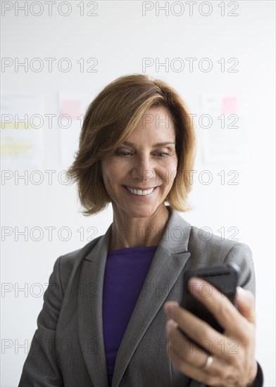 Caucasian businesswoman using cell phone in office