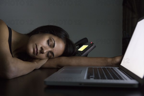 Businesswoman sleeping at desk at night