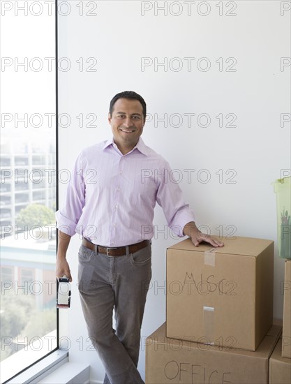 Hispanic businessman with cardboard boxes in new office