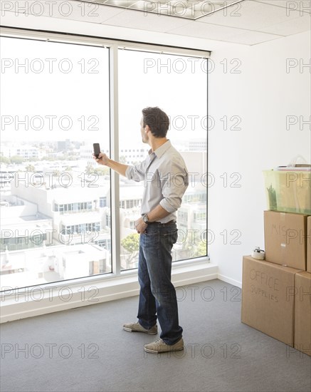 Hispanic businessman taking photograph in new office