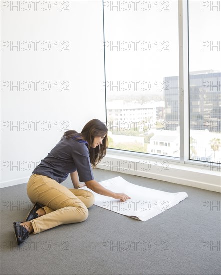 Woman reading blueprints in empty office